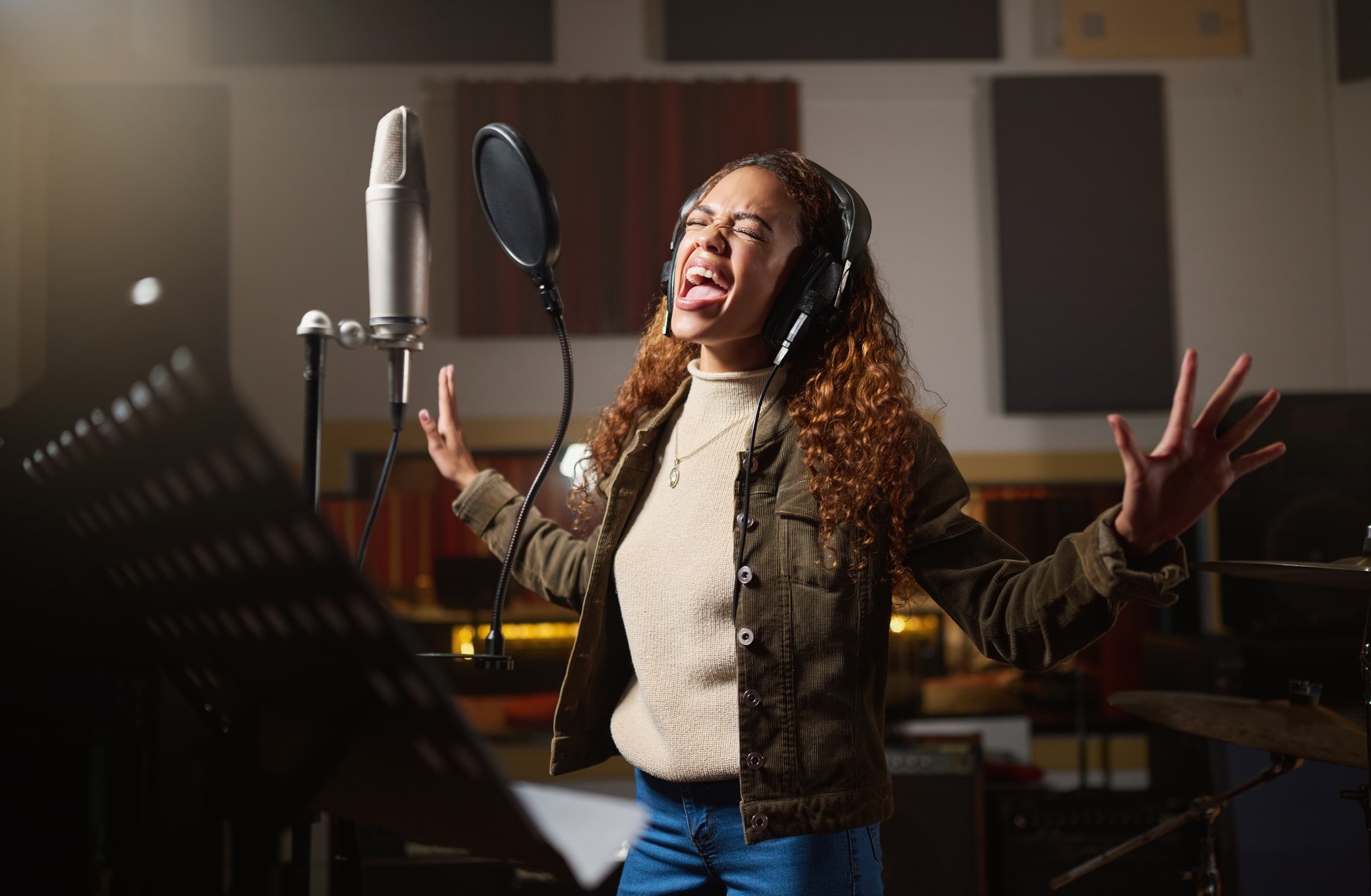 Music, streaming and woman recording in studio in home, singing into microphone with headphones and talent. Technology, art and creative influencer or musician with live stream song for record label.